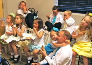 Children, and a few dads, enjoying a movie in the children/groom's room.